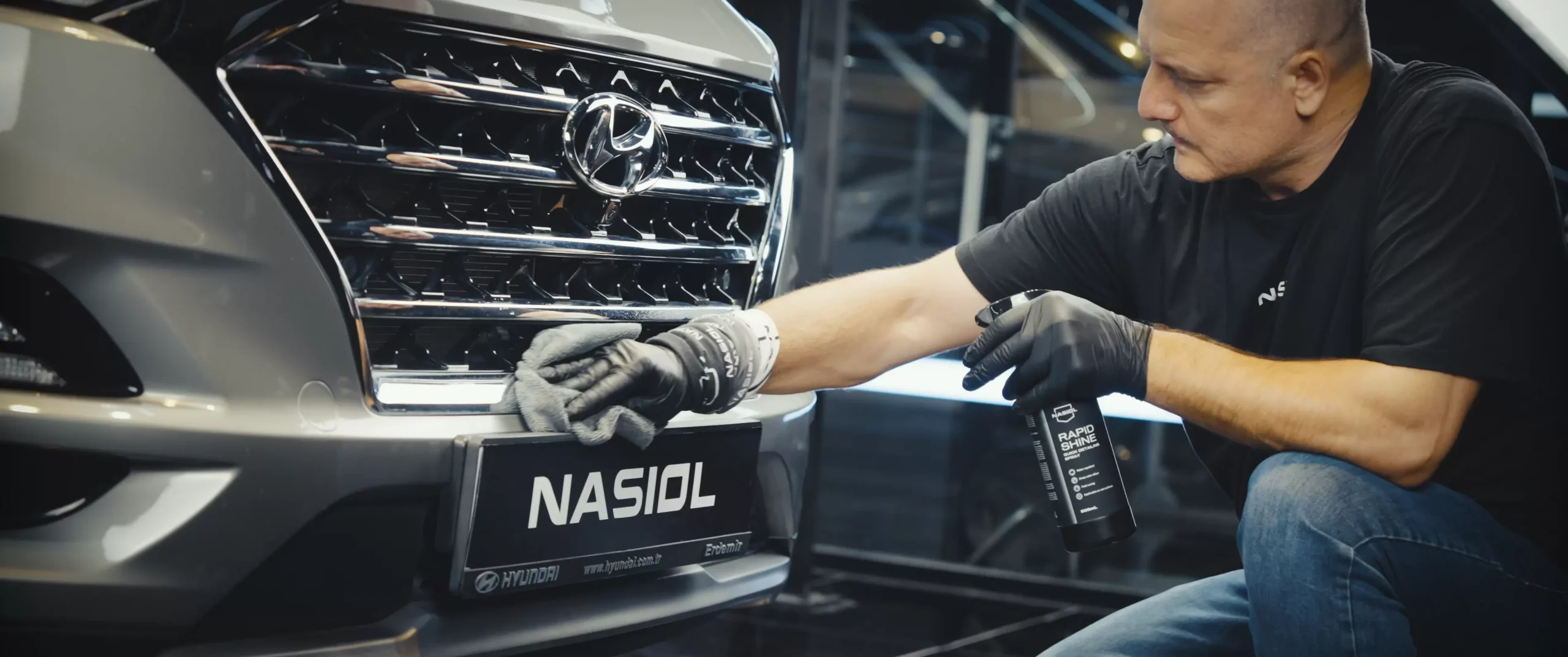 Detailer applying Nasiol RapidShine spray to a vehicle, enhancing shine and protection with an effortless wipe-on application.